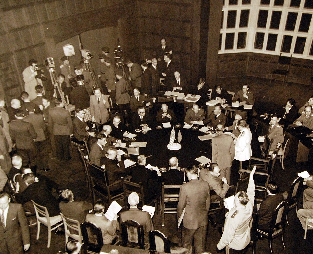 80-G-700186: Potsdam Conference, 17 July – 2 August 1945. Prime Minister Clement Atlee, President Harry S. Truman and Premier Joseph Stalin (standing) about to resume talks around the table in conference room at Potsdam, Germany. Photographed by CPhoM William Belknap Jr., released July 26, 1945. U.S. Navy Photograph, now in the collections of the National Archives. (2016/02/23).
