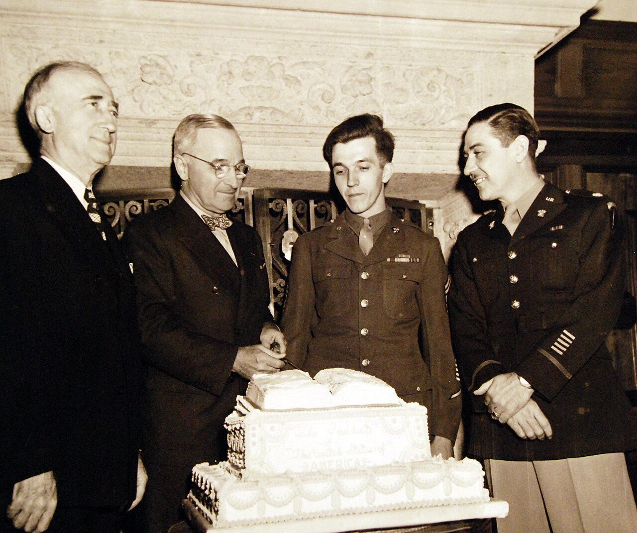 80-G-700193: Potsdam Conference, 17 July – 2 August 1945. At the “Little White House” in Potsdam, Germany, President Harry S. Truman is receiving a cake from one of the Army’s cooks. Left to right: Secretary of State James F. Byrnes, the President, Master Sergeant Benedict A. Tamol and Major Lennox. Photographed by CPhoM William Belknap Jr., released July 28, 1945. U.S. Navy Photograph, now in the collections of the National Archives. (2016/02/23).