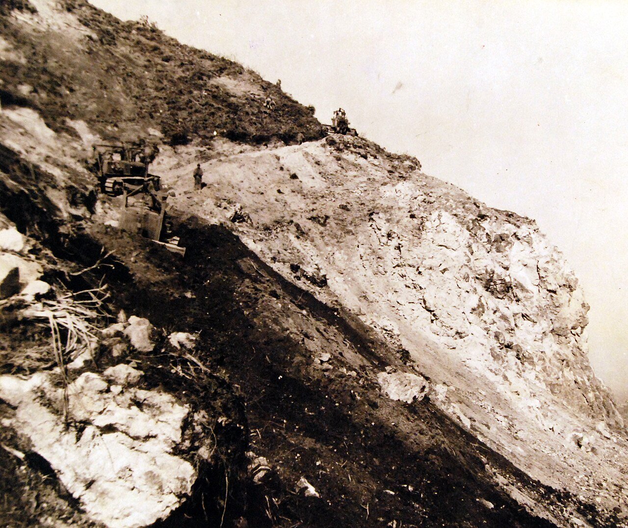 80-G-700213: Progress is made by CB’s building a road to the top of Mount Suribachi on Iwo Jima. A road grader moves easily to the side of the cliffs. Photograph released August 7, 1945. U.S. Navy Photograph, now in the collections of the National Archives. (2016/02/23).