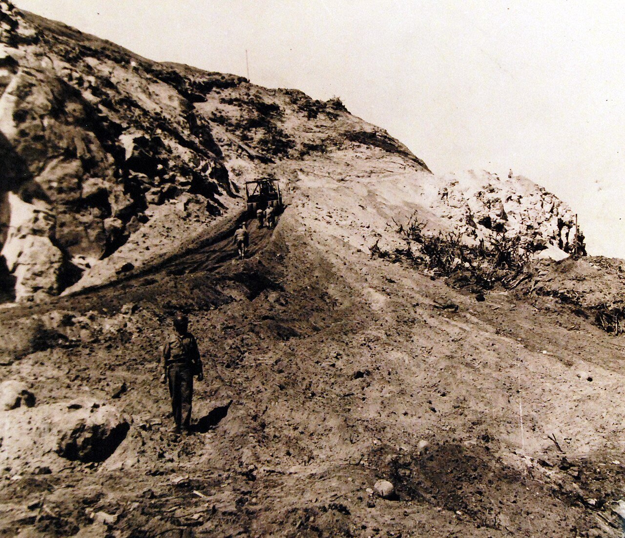 80-G-700214: Progress is made by CB’s building a road to the top of Mount Suribachi on Iwo Jima. A road grader moves easily to the side of the cliffs. Photograph released August 7, 1945. U.S. Navy Photograph, now in the collections of the National Archives. (2016/02/23).