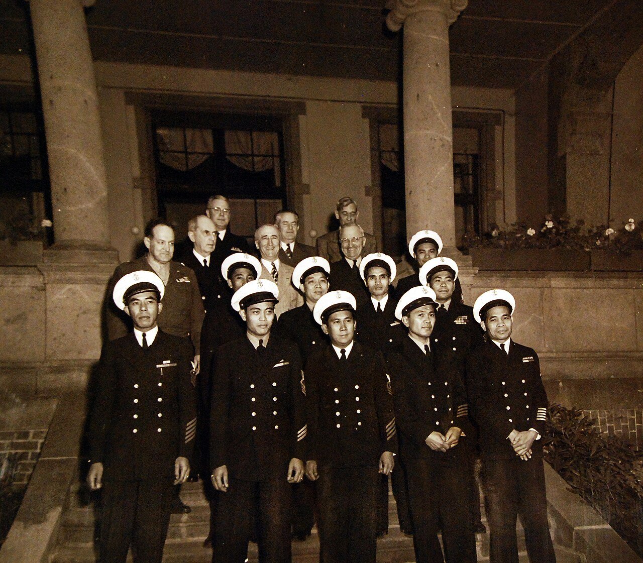 80-G-700273: Potsdam Conference, 17 July – 2 August 1945. Filipino men in fore ground with President Harry S. Truman and his party on the steps of the “Little White House” at Potsdam, Germany. Shown: General Harry Vaughn; Fleet Admiral William D. Leahy; Secretary of State J. F. Byrnes and President Harry S. Truman. Photographed released July 30, 1945. U.S. Navy Photograph, now in the collections of the National Archives. (2016/02/23).