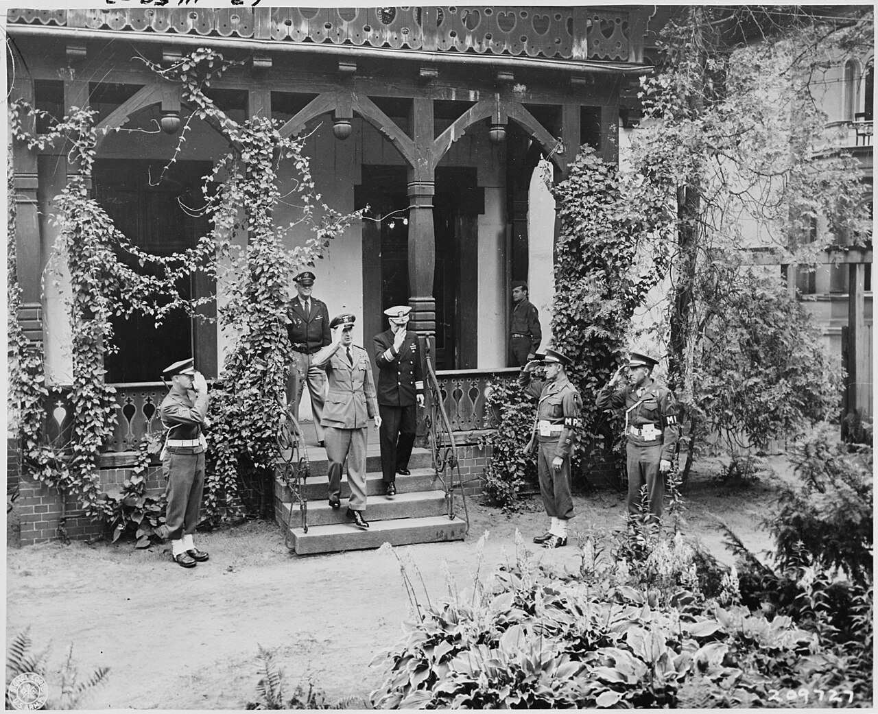 Adm. Ernest J. King, left, and Rear Admiral Howard A. Flanigan salute MPs as they leave Cecilienhof Palace, scene of…