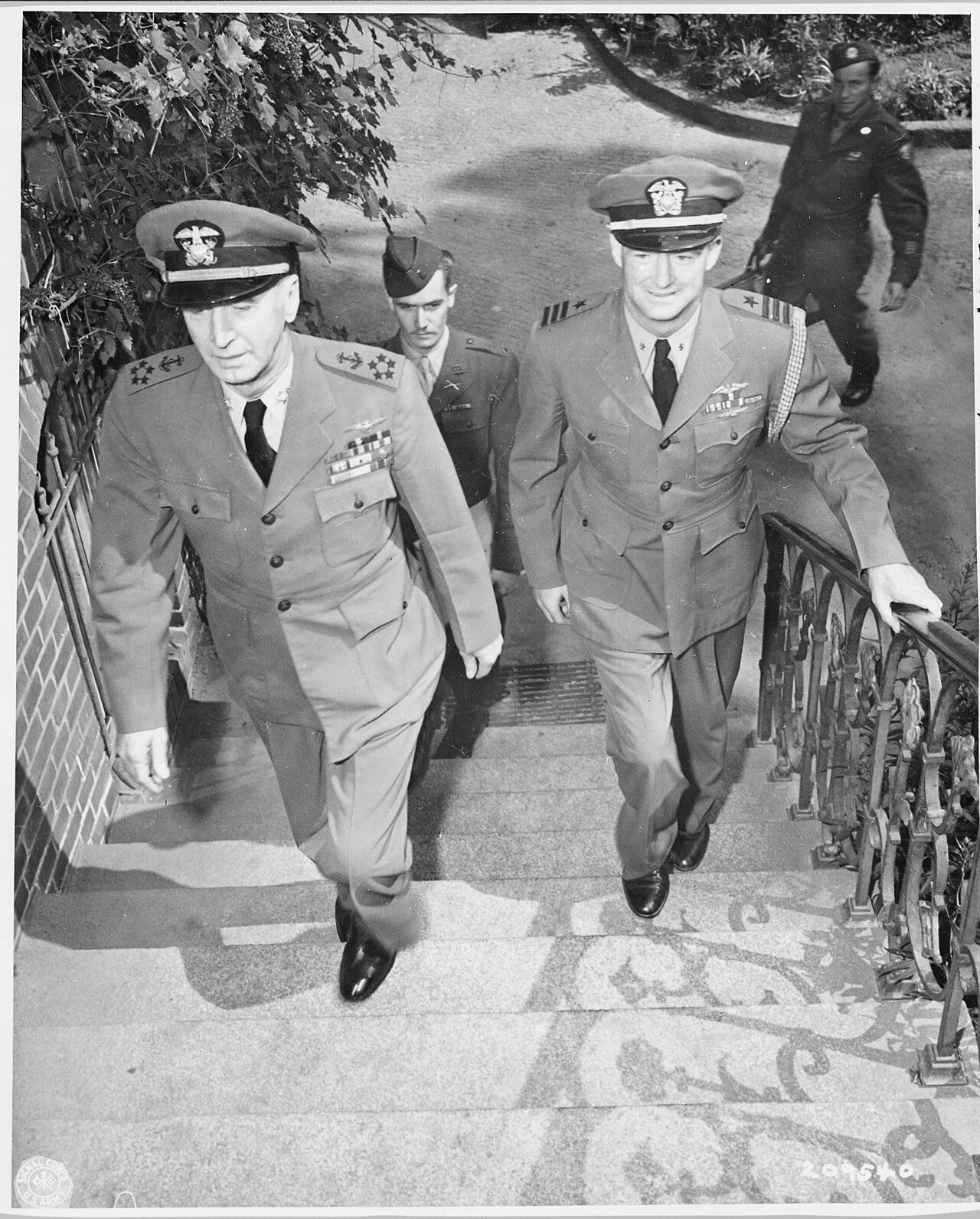 Fleet Admiral Ernest J. King (left), accompanied by Commander R. E. Dornin, mount the steps to their quarters near…