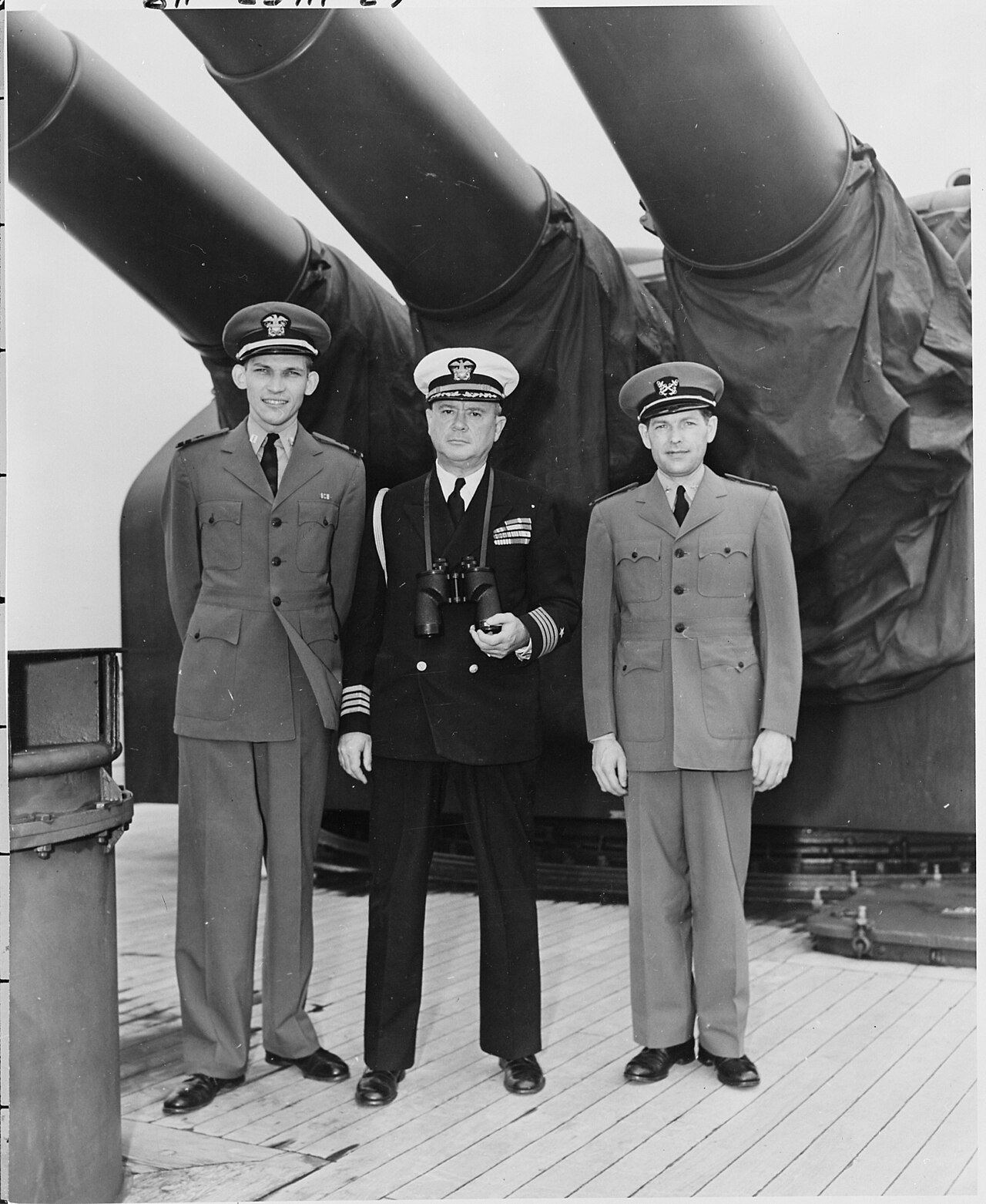 L to R, Lt. George Elsey, Captain James Vardaman, and ship's clerk Edwin L. Hoying stand on the deck of the U. S. S.…