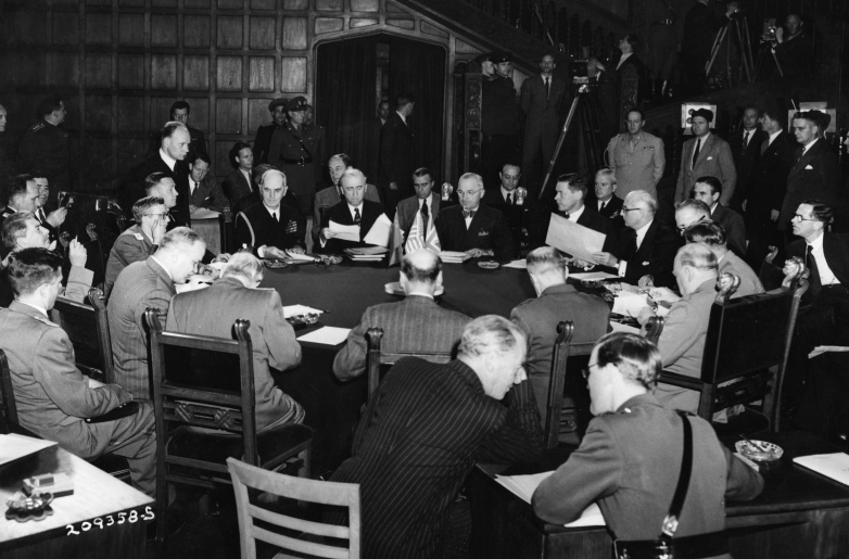 Truman, Churchill, Stalin at their first meeting at the Potsdam Conference, 1945 Jul 17. Original description: The Opening Session of the Potsdam Conference poses for photographers. President Harry S. Truman is near the center at the back end of the table, wearing a bow tie. Clockwise around the table, starting at President Truman: Charles Bohlen; two unidentified men; British foreign minister Anthony Eden; Prime Minister Winston Churchill; unidentified British military officer; Clement Attlee; unidentified man; Soviet foreign minister Vyacheslav Molotov; Joseph Stalin; two unidentified men; Admiral William D. Leahy; Secretary of State James Byrnes. Also present are Edwin Pauley (behind Byrnes, partly obscured); Captain James K. Vardaman (behind Bohlen, partly obscured); Major General Harry Vaughan (standing behind Vardaman); and Averell Harriman (seated on Vardaman's left). All others are unidentified. From the album "President's Trip to the Berlin Conference Vol. 2 of 2." Date(s) July 17, 1945
