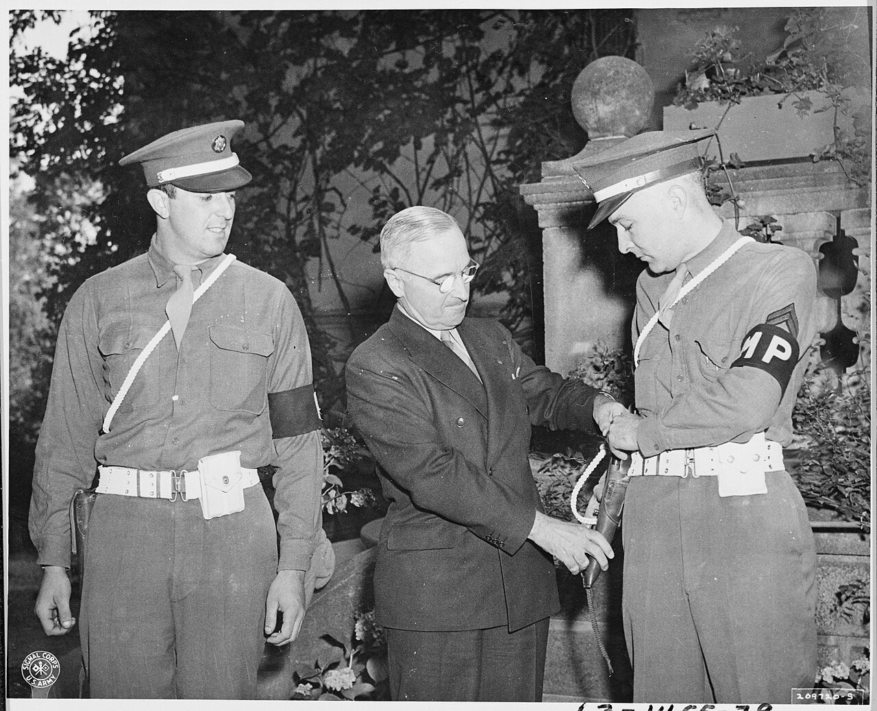 President Harry S. Truman examines the pistol of Cpl. John Tuehy, during the Potsdam Conference in Germany as Pvt.…