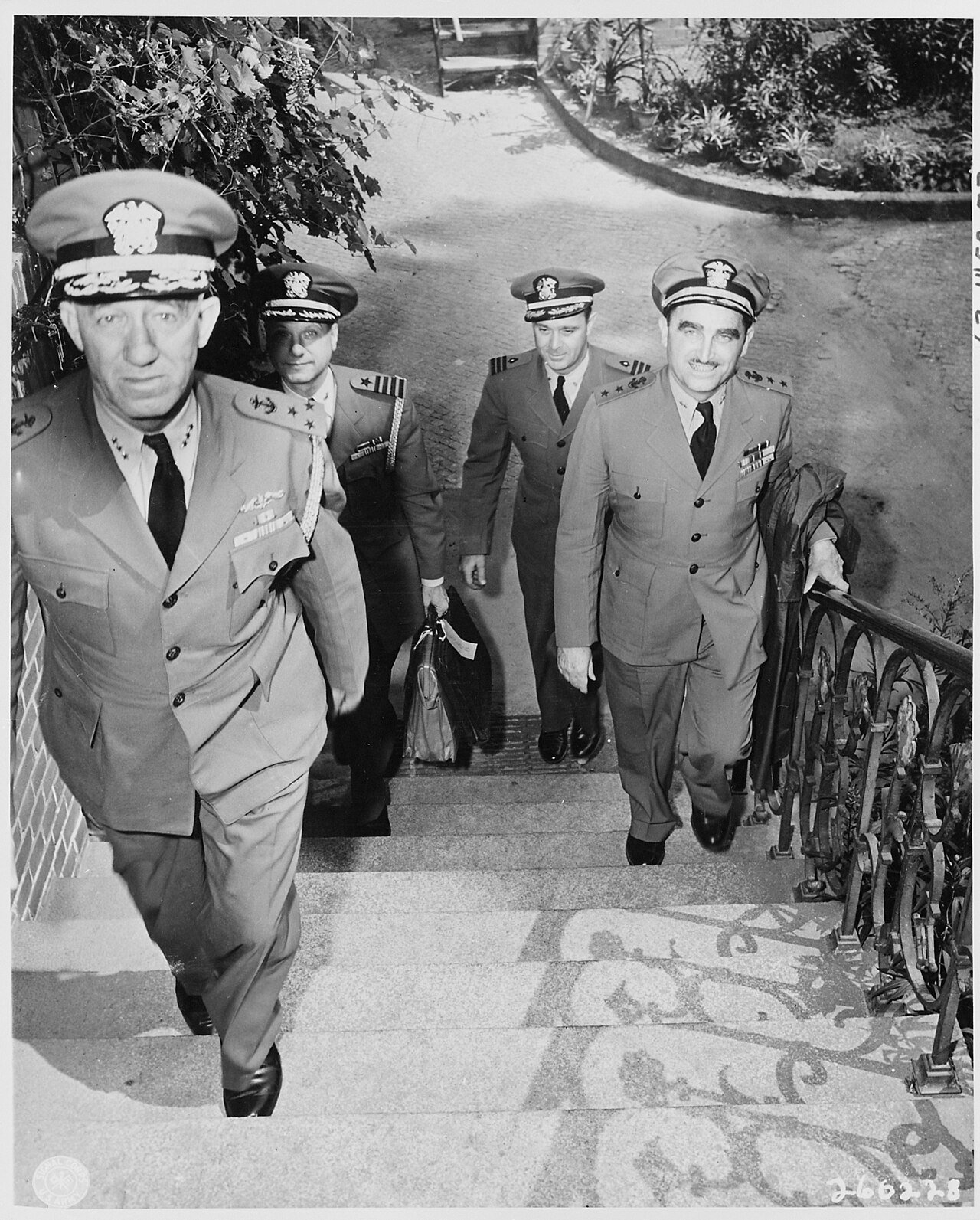 The staff officers of Fleet Admiral Ernest J. King, U. S. Navy, ascend steps to their quarters near the "Little White…