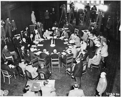 Delegates seated around the conference table at Cecilienhof Palace during a session of the Potsdam Conference in…