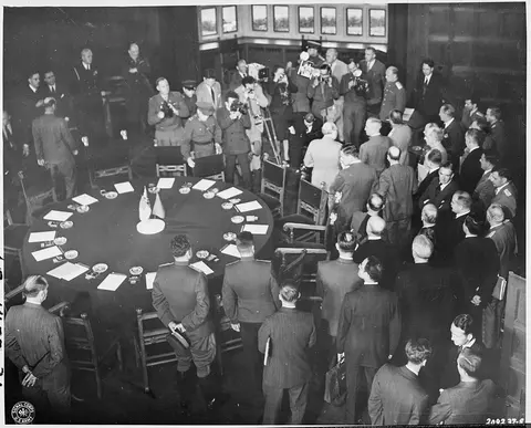 Participants in the Potsdam Conference in Germany stand mingling in the conference room at Cecilienhof Palace. The…
